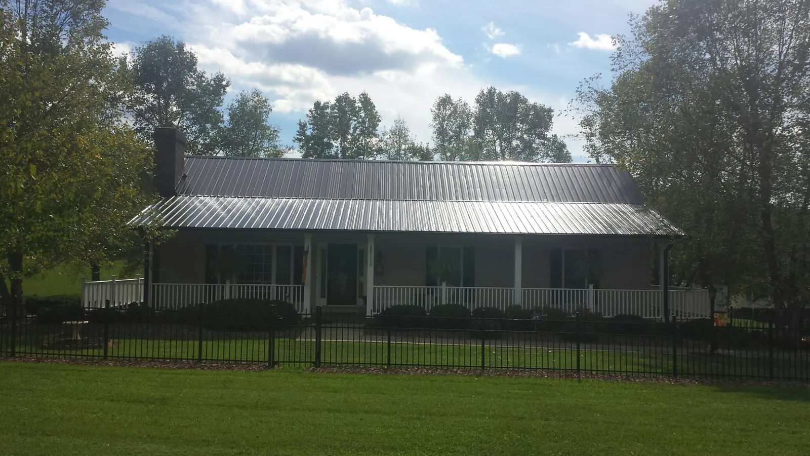 Gray metal roof on a brick ranch with a full width front porch — Gutter Guard Installation work by our crew in Bath